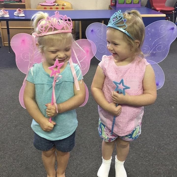 Two toddlers dressed up as fairies, laughing together